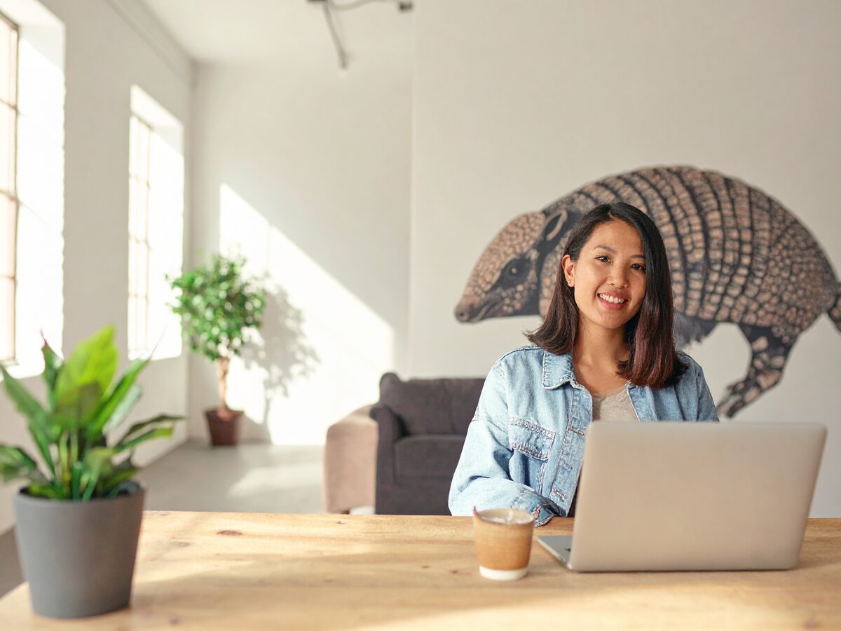 Image of a woman sitting across the table looking at the viewer. She appears happy and ready to help.